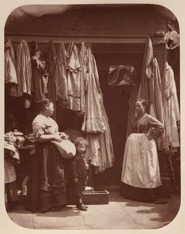 ロンドン、1877 年。古着屋。商品は外に吊る。