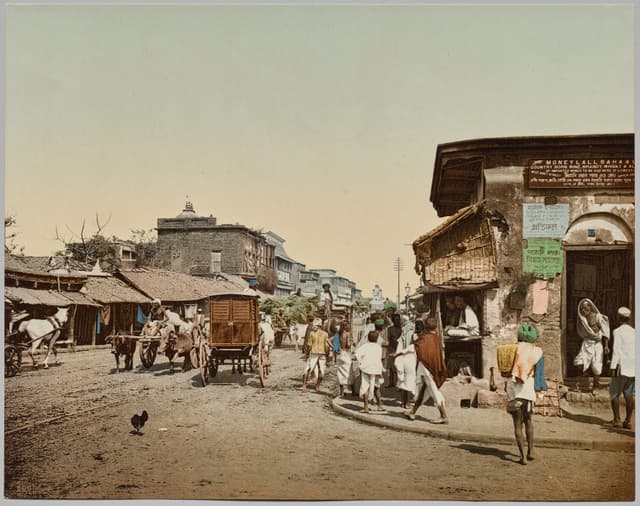 Crowded street, hand-coloured, 1900. Energy comes from the crowd, not the hero. Cast the extras first.